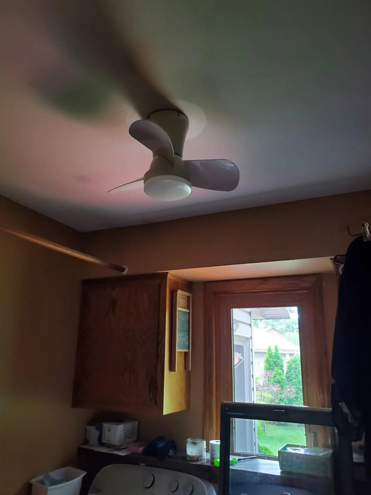 An industrial-style or farmhouse ceiling fan featuring dark blades and a distinctive caged light fixture, adding a rustic yet modern touch to any room.