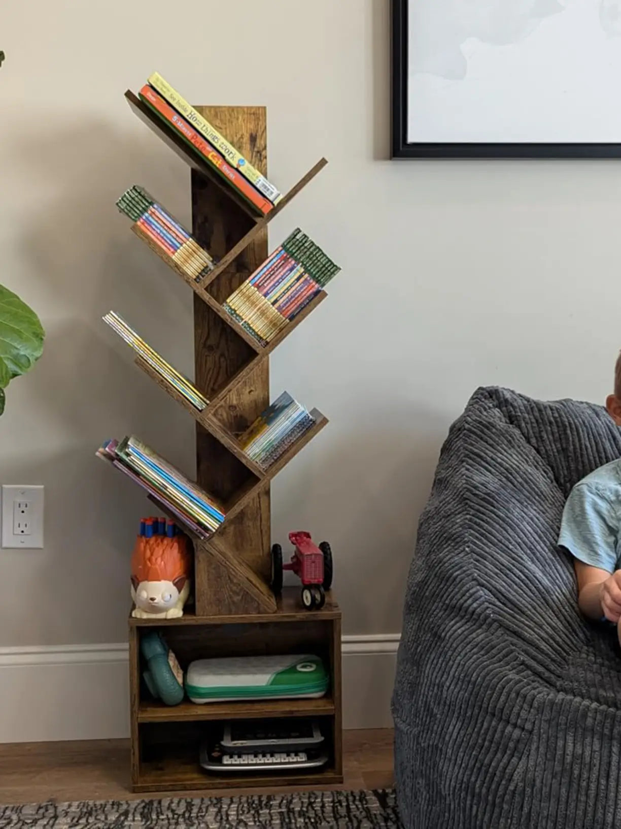 A tall tree bookshelf in a dark wood finish, standing prominently in a living room, providing an artistic and space-saving way to organize books and display decor.