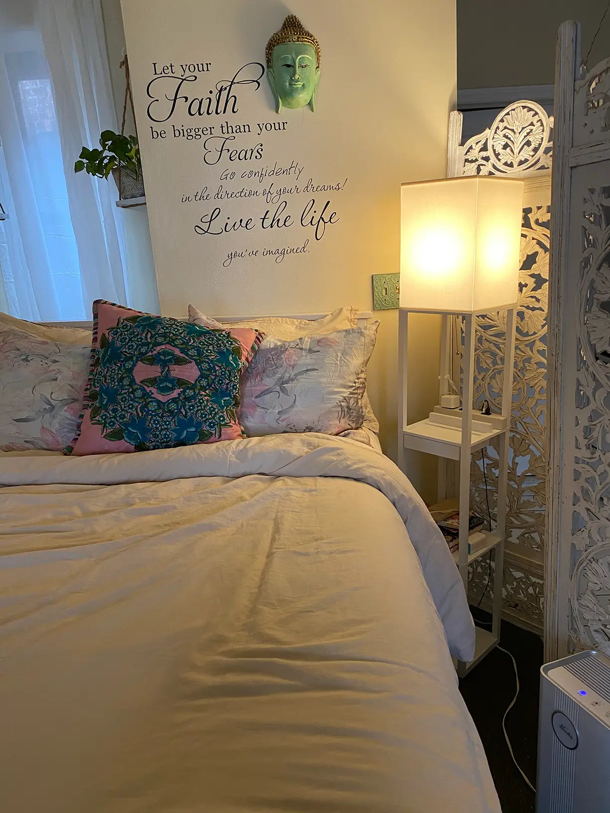 A white shelf floor lamp with multiple tiers and a square fabric shade, illuminating a dorm room or small living space, ideal for combined lighting and storage.