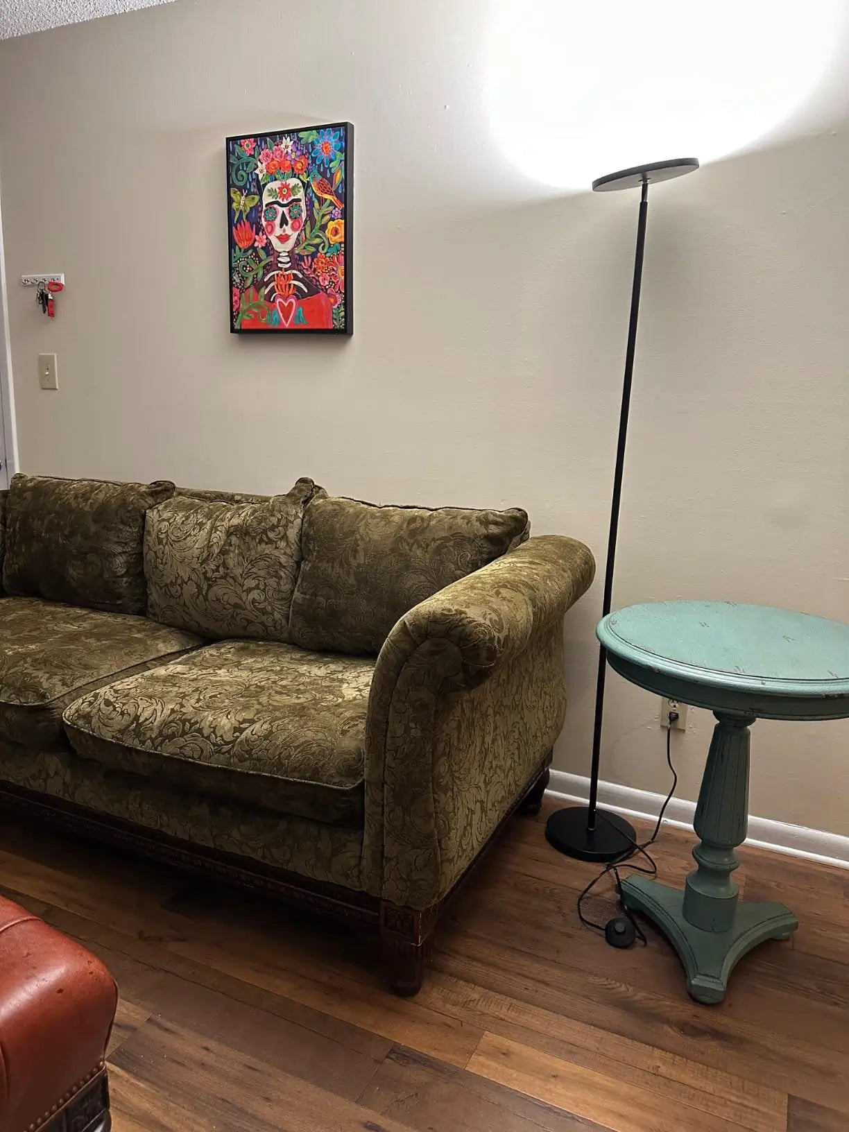 An elegant torchiere floor lamp with a brushed metal finish and a classic upward-facing shade, enhancing the ambiance of a sophisticated living room with a large sofa and decorative throw pillows.