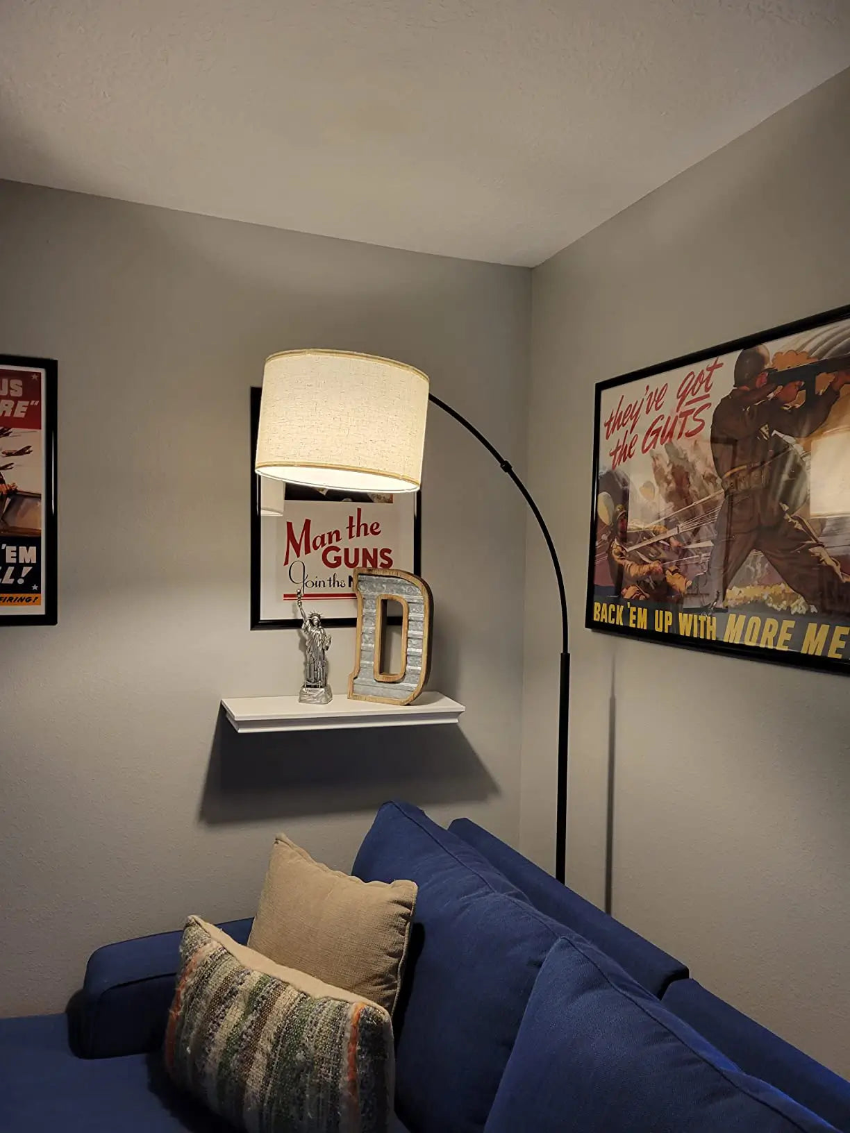 A mid-century modern arc floor lamp with a brushed nickel finish and a large, wide dome shade, providing overhead illumination for a comfortable grey armchair in a contemporary living space.