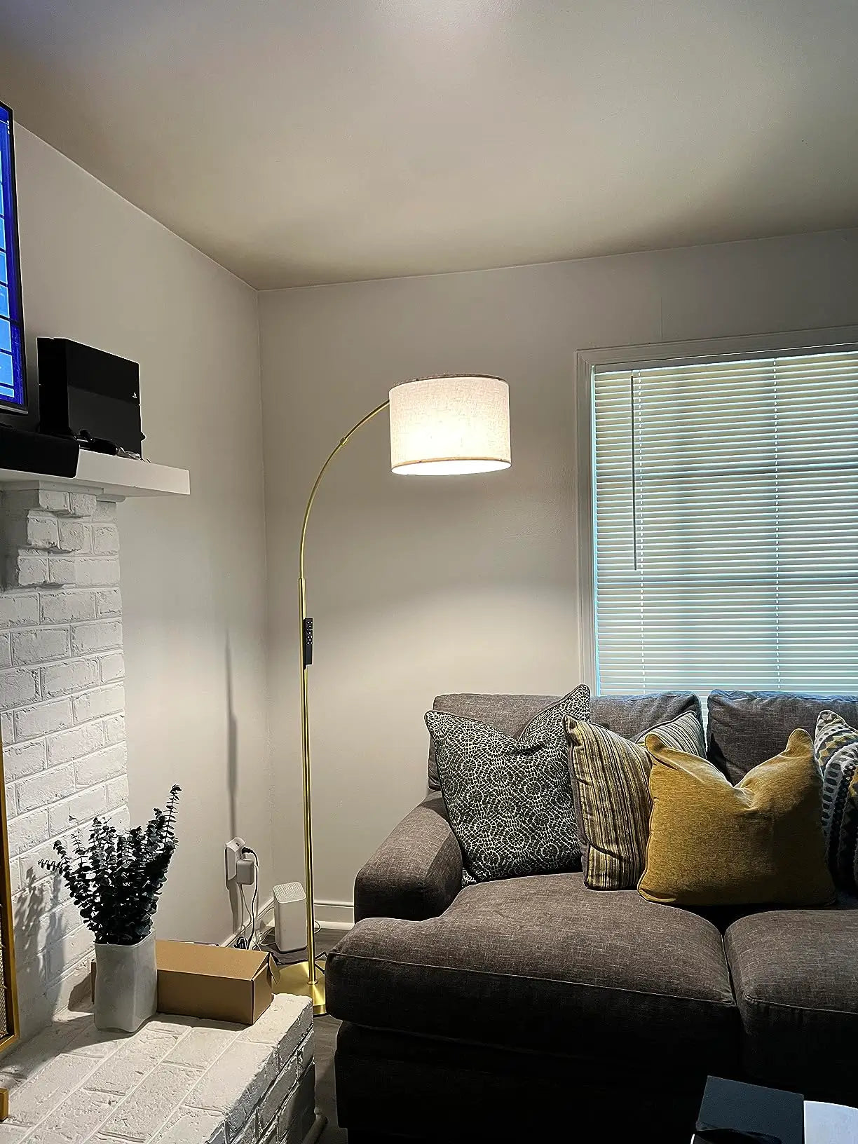 A minimalist black arc floor lamp with a simple bowl-shaped shade, elegantly curving over a light-colored sectional sofa in a modern living room, adding a stylish lighting accent.