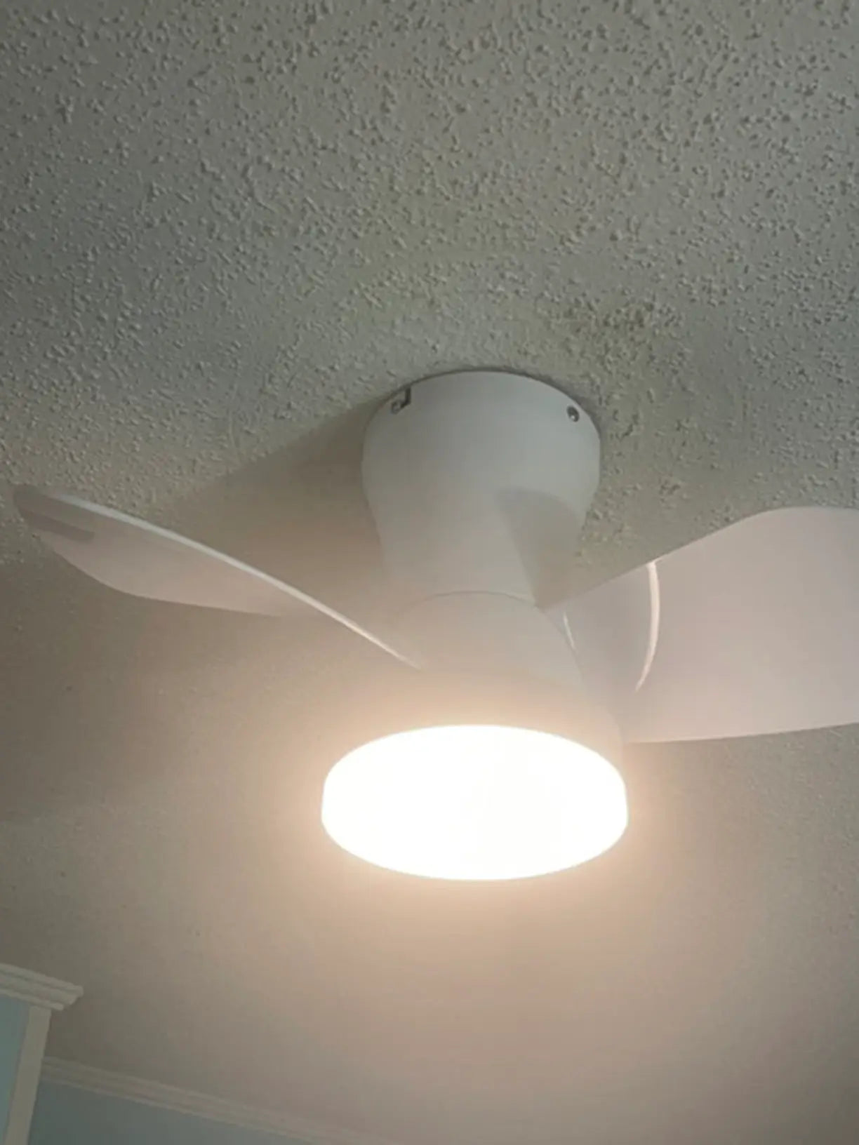 A sleek, modern ceiling fan with an integrated LED light kit and remote control, designed to provide both efficient air circulation and ambient lighting in a contemporary living space.
