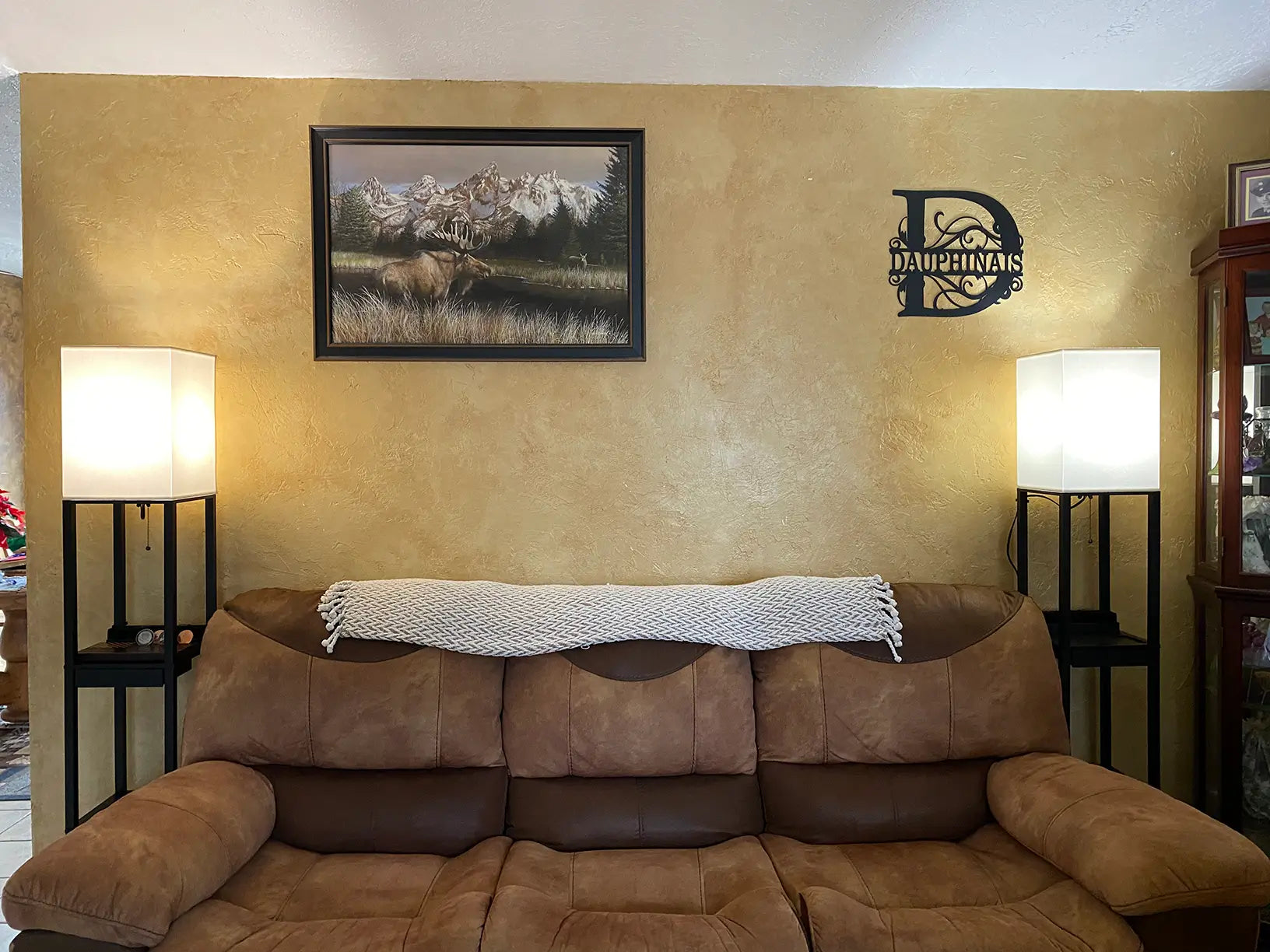 A modern dark wood shelf floor lamp with three open display shelves and a cream fabric shade, providing both lighting and storage in a contemporary living room.