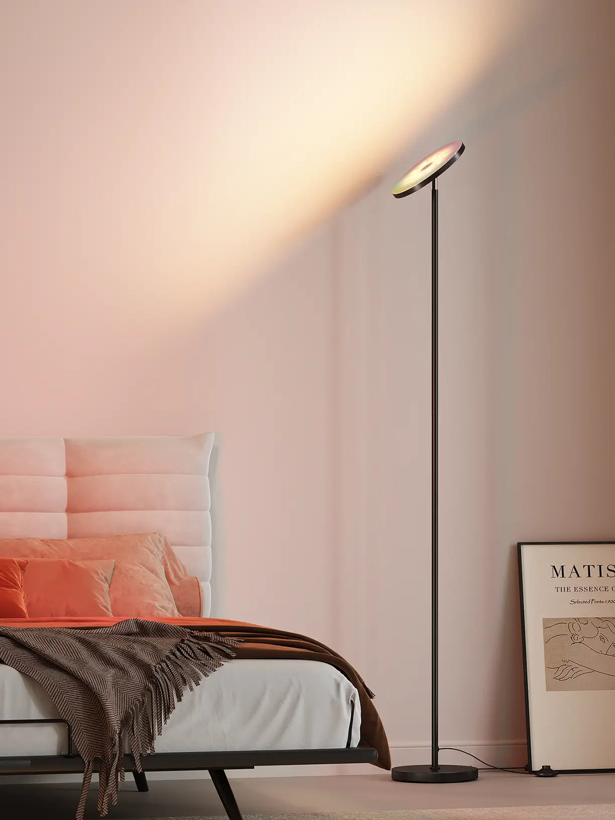 A sleek, modern LED torchiere floor lamp with a thin metal stand and an upward-facing light dish, casting bright ambient light in a contemporary living room with a neutral sofa and simple decor.