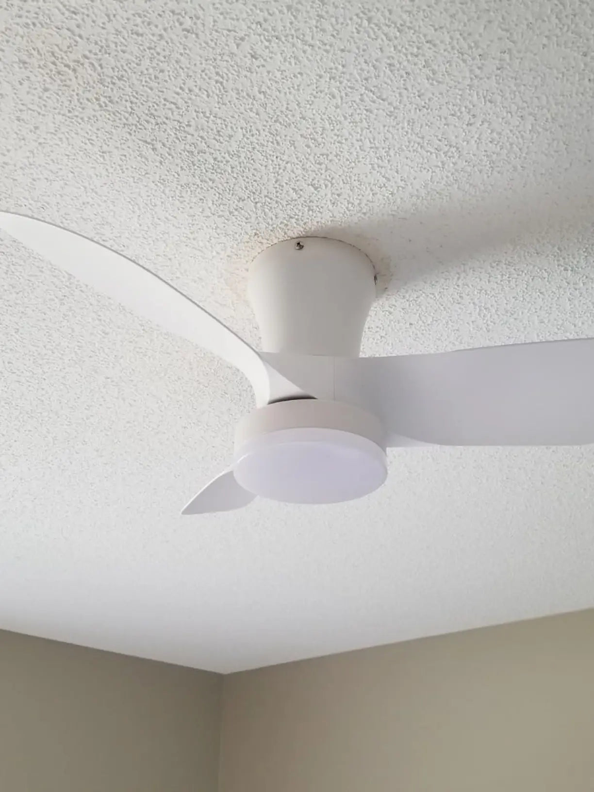 A modern white ceiling fan with a sleek, minimalist design and an integrated light, providing both effective air circulation and ambient illumination for contemporary interiors.