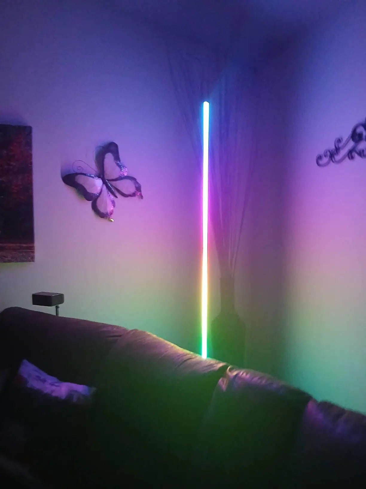 A smart RGB floor lamp showcasing a gradient of colors from its slender form, perfect for creating dynamic ambient lighting in a tech-savvy home