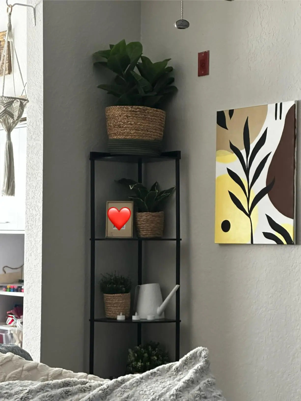 A tall black corner shelf stand with a sturdy metal frame, presenting an industrial design ideal for displaying various items in a modern or urban interior.